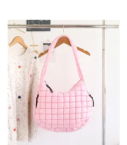 Chic pink quilted nylon hobo bag hanging on clothing rack in soft minimalist setting