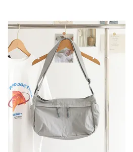 Lässige graue Nylon-Umhängetasche an einem Holzbügel in einem minimalistischen Studio