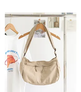 Minimalistische beige Nylon-Umhängetasche, die lässig an einem Kleiderständer hängt