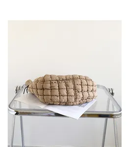 Close-up of khaki quilted nylon shoulder bag on a modern transparent side table