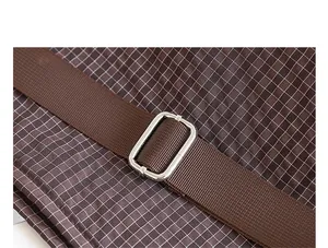 Detalle de la correa de nailon marrón ajustable con hebilla plateada en bolso de cuadros