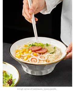 Detailed view of a white ceramic fluted ramen bowl with an elegant gold rim and noodles