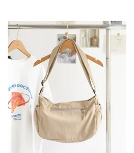Nahaufnahme einer minimalistischen beigen Nylon-Umhängetasche an einem Kleiderbügel