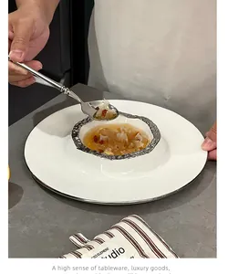 Gros plan détaillé d'une assiette volcan en céramique blanche avec bord argenté.