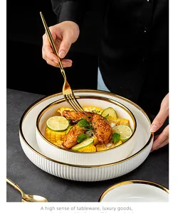 Assiette creuse de luxe en céramique blanche avec bord doré et texture nervurée élégante.