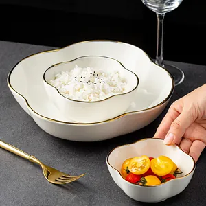Eleganti ciotole in ceramica a forma di petalo con bordo dorato per frutta e insalate.