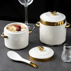 Elegante juego de ollas de cerámica blanca con borde dorado, tapa y cuchara de sopa.