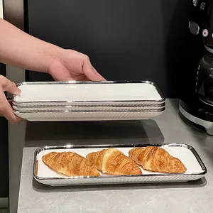 Assiette rectangulaire en céramique blanche avec bord argenté pour collations ou sushi.