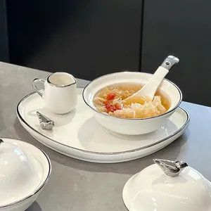 Elegante witte keramische dessertkomset met zilveren vogelaccenten en een dienblad.