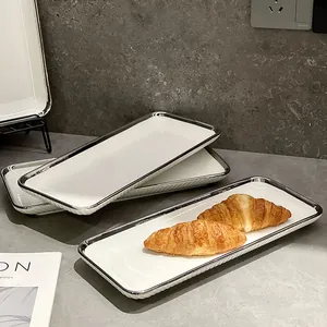 Assiette à dessert rectangulaire en céramique avec bord argenté élégant sur un comptoir