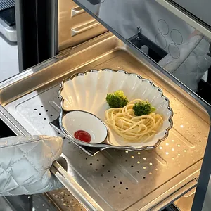 Piatto in ceramica a forma di conchiglia con bordo argento, mostrato dentro un forno