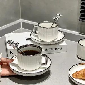 Juego de taza de café y platillo de cerámica blanca con borde plateado y cuchara de oso.