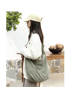 Large sage green corduroy hobo crossbody bag styled by a model in an outdoor setting