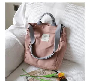 Detailed view of a pink canvas tote bag with grey straps placed on a textured white sofa