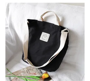 Detail of black canvas tote bag with adjustable cream shoulder strap and top handles