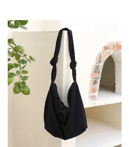 Close-up of black corduroy hobo bag with unique knotted shoulder strap design