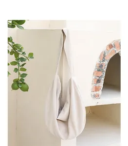 Detalle artístico de un bolso hobo de pana beige colgado contra un arco rústico de ladrillo.