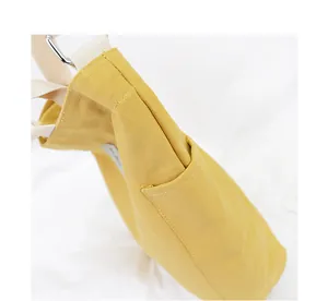 Close-up detail of a minimalist yellow canvas tote bag showing side pocket and strap