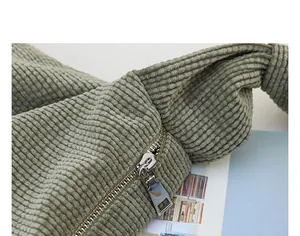 Macro view of the high-quality metal zipper and knotted strap on a green corduroy bag.