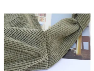 Close-up of green corduroy crossbody bag featuring a unique knotted shoulder strap detail.