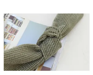 Detailed view of the knotted shoulder strap on a green corduroy crossbody bag