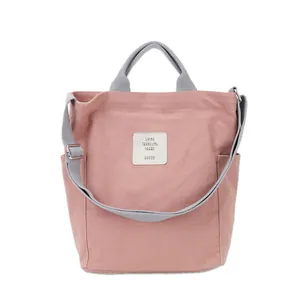 Stylish pink canvas tote bag with gray handles and adjustable shoulder strap for casual use