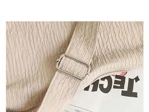 Detailed close-up of pleated beige nylon bag strap featuring silver metal buckle