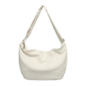 Minimalist white nylon shoulder bag with crinkled pleated texture, adjustable strap