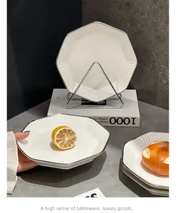 Détail d'une assiette en céramique blanche octogonale avec bord argenté dans un décor