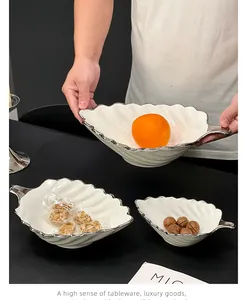 Détail de bols en céramique blanche en forme de feuille avec bord argenté pour desserts