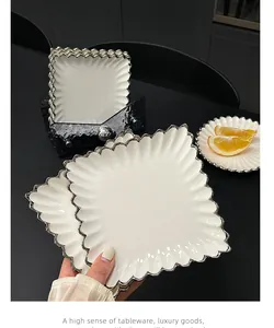 Detailansicht von luxuriösem weißem Keramikteller mit silbernem Wellenrand und Ständer.