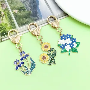 Makrodetail von Emaille-Blumen-Schlüsselanhängern mit goldfarbenen Herz-Karabinern.