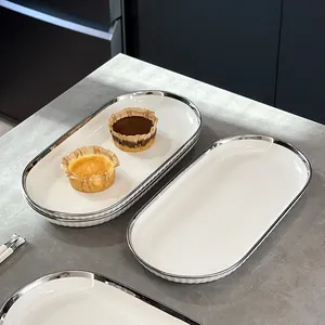 Σκανδιναβικό λευκό κεραμικό οβάλ πιάτο με ασημένιο χείλος σε γκρι πέτρινο πάγκο