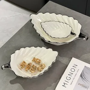 Lot de bols à salade élégants en céramique blanche en forme de feuille avec bord argenté.