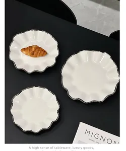 Vue détaillée d'assiettes en céramique blanche avec d'élégants bords argentés festonnés