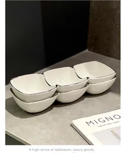Close-up of elegant white three-compartment ceramic snack dish with silver rim detail