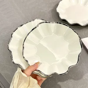 Assiette en céramique blanche avec élégant bord argenté festonné pour dîner