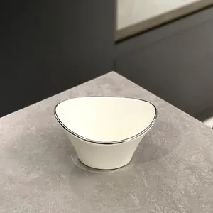 Elegante ciotola per snack in ceramica bianca con bordo argentato su superficie in pietra