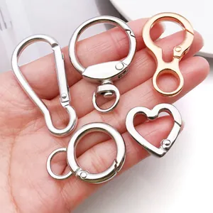 Close-up of various metal heart and round shaped keychain hooks held in hand