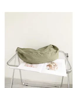 Detailansicht einer grünen Teigtasche mit Waffelstruktur auf einem modernen Stuhl.