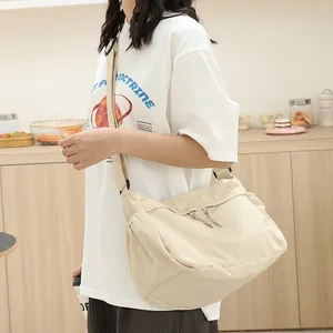 Japanische cremefarbene Nylon-Umhängetasche an einem Model in einem minimalistischen Café