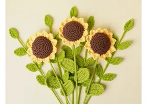 Primer plano de tres girasoles hechos a mano a ganchillo con pétalos amarillos y hojas verdes.