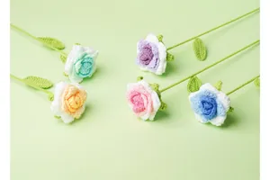 Vista detallada de varias rosas de ganchillo hechas a mano sobre un fondo verde
