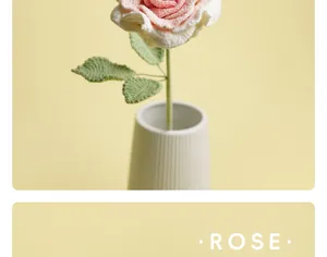 Detailed view of a handmade pink and white crocheted rose in a minimalist white vase