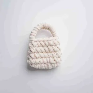 Detalle de un mini bolso artesanal hecho a mano con hilo de lana grueso color blanco crema