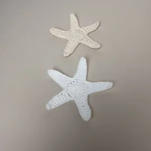 Detailweergave van twee handgemaakte witte en crème gehaakte zeesterren
