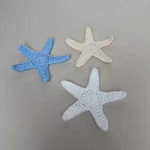 Detailweergave van handgehaakte zeesteraccessoires in blauw, beige en wit voor tassen