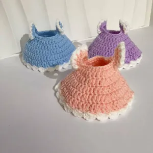 Close-up of handmade crochet bunny dresses for 20cm plush cotton dolls in pastel colors.