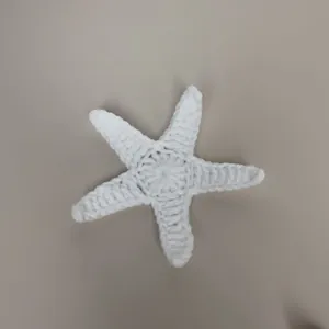 Gedetailleerd aanzicht van handgehaakt wit wollen zeesteraccessoire voor tassen.