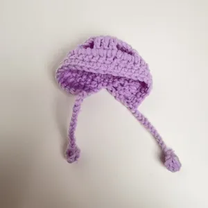 Detailed view of the purple hand-knitted miniature doll hat with long braided straps